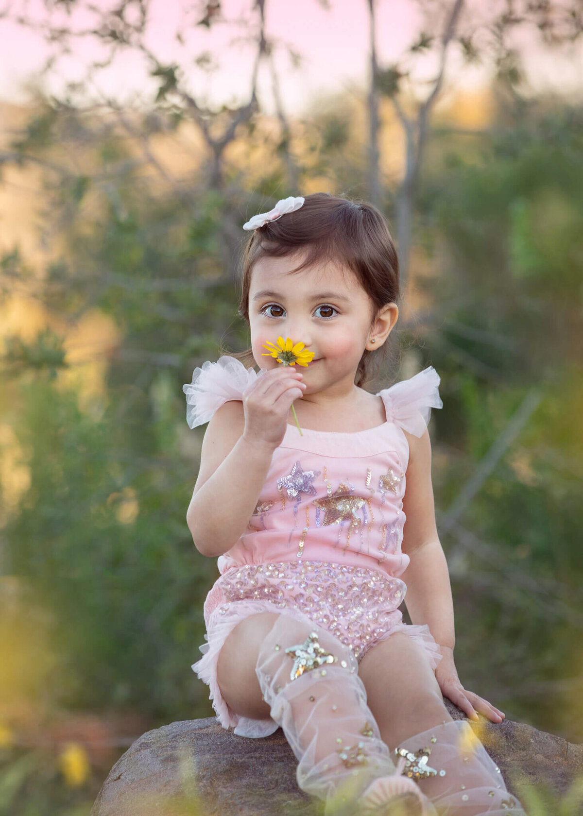Little girl smelling flowers at the park wearing a pink tutu du monde outfit - Los Angeles Children’s Photographer