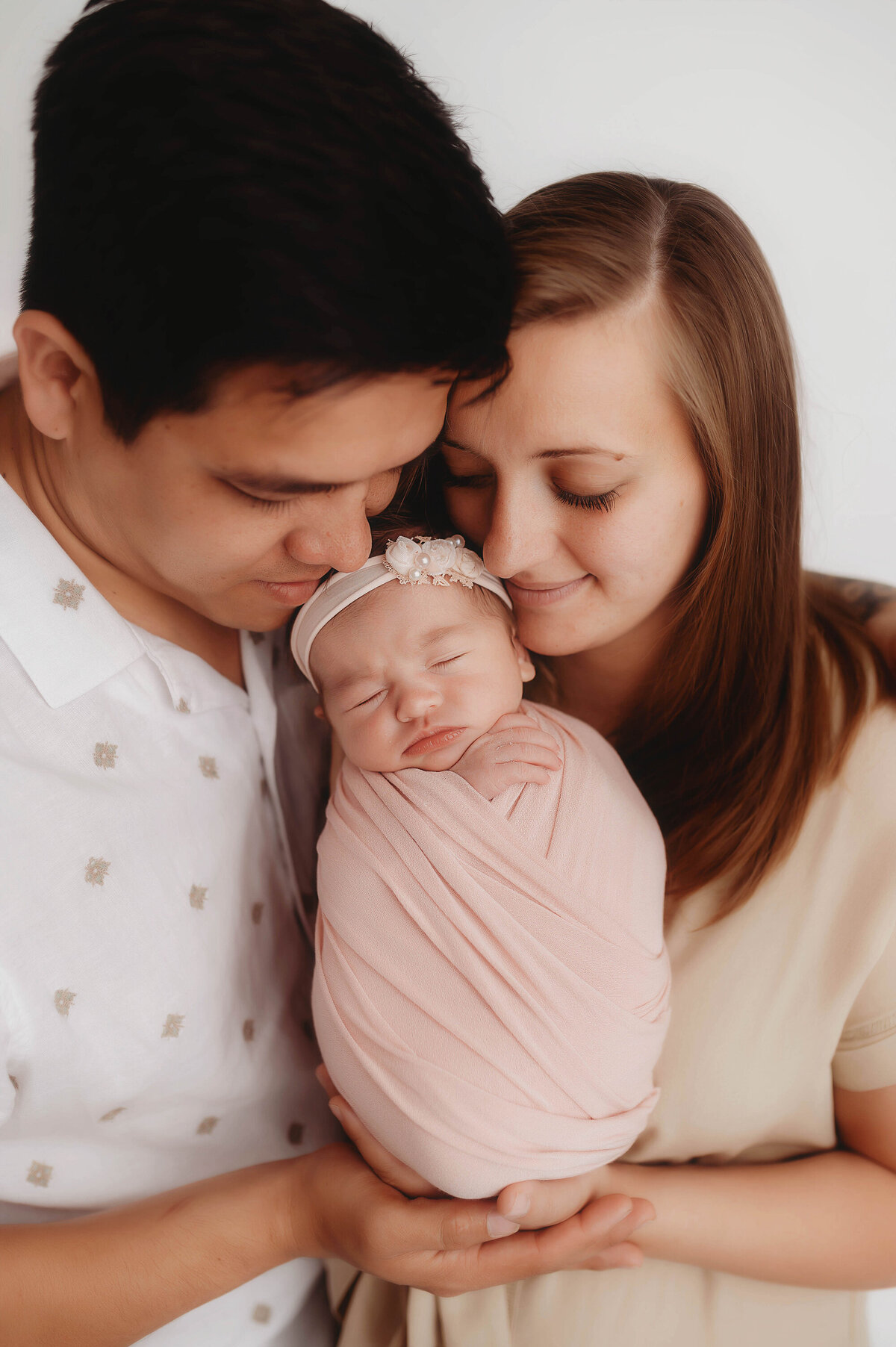 Parents embrace their infant daughter during Newborn Portrait Session in Charleston, SC Newborn Photography Studio.