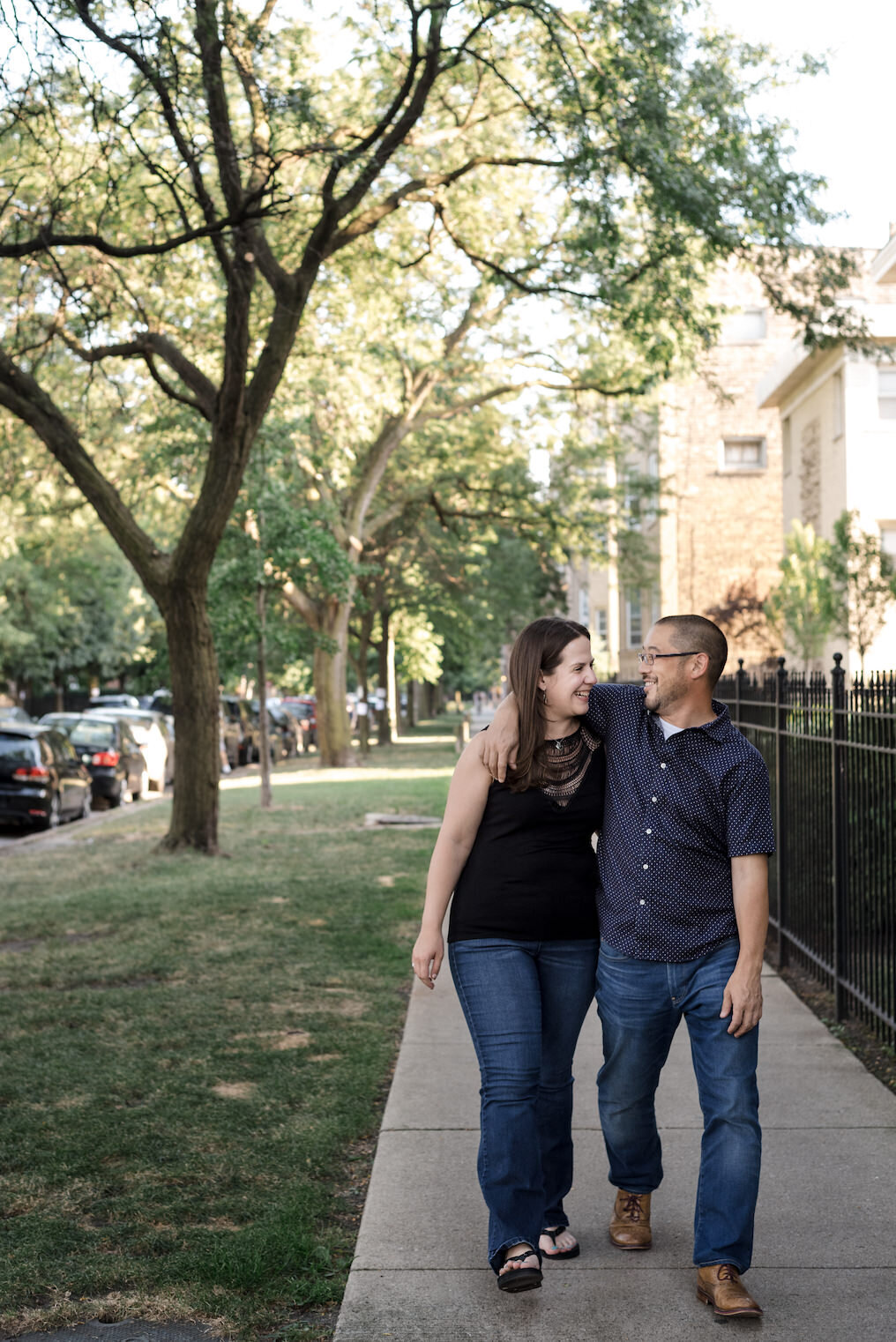 Couple walks down the sidewalk, laughing at one another, in the Ravenswood neighborhood of Chicago