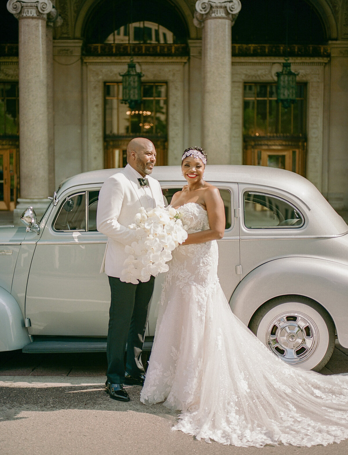 Bride and groom in sunlight with vintage wedding car in Detroit, Michigan