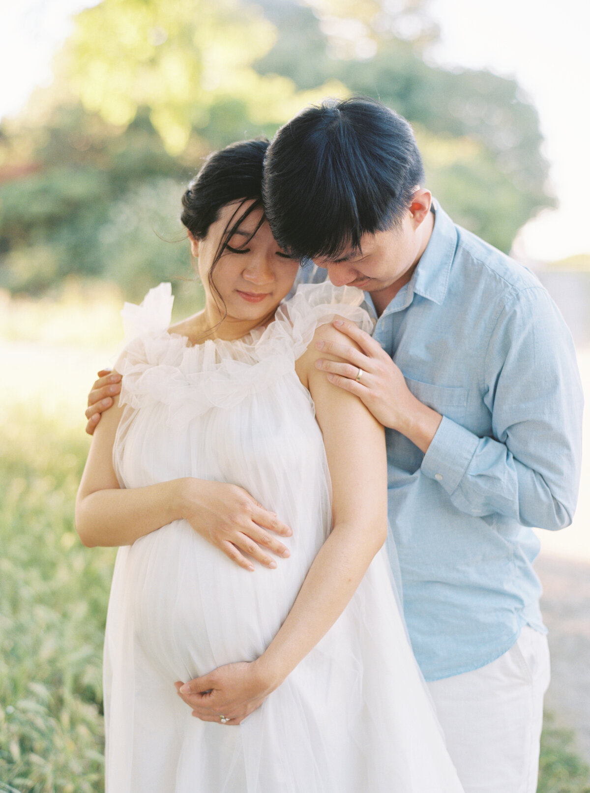 Maternity Photos captured on film at Seattle's Golden Garden beach. Mom in white dress, dad in blue linen shirt. 