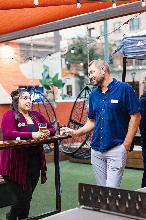 Man and woman hold drinks and chat at a social event.