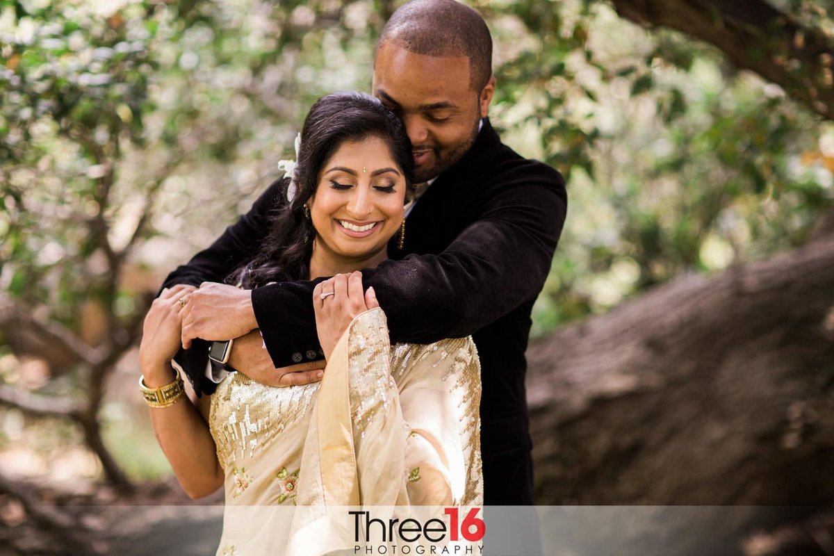 Groom embraces his Bride from behind outside the courthouse