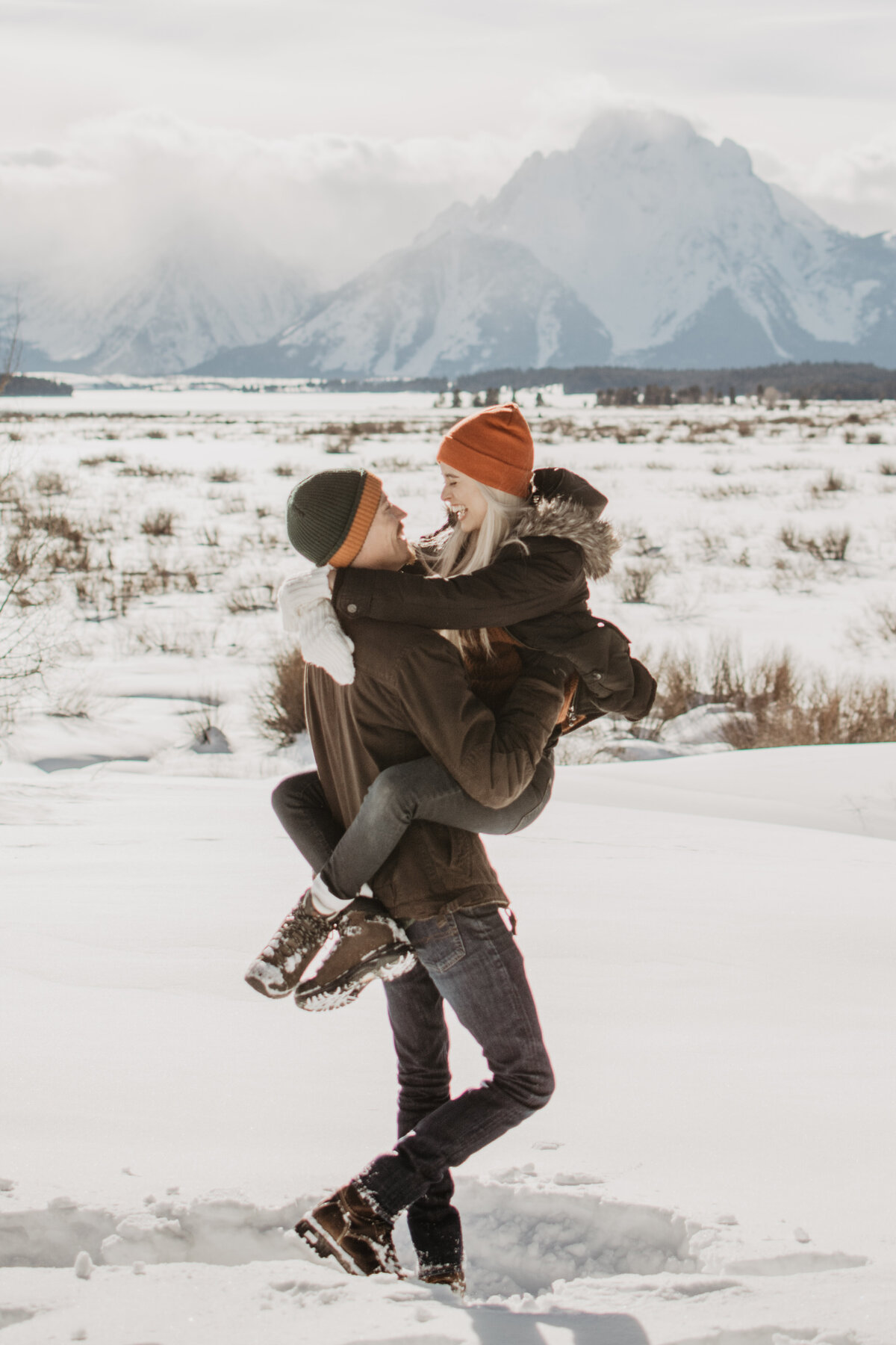man carrying his fiance in the snow through Jackson hole for their engagement session by jackson hole photographers