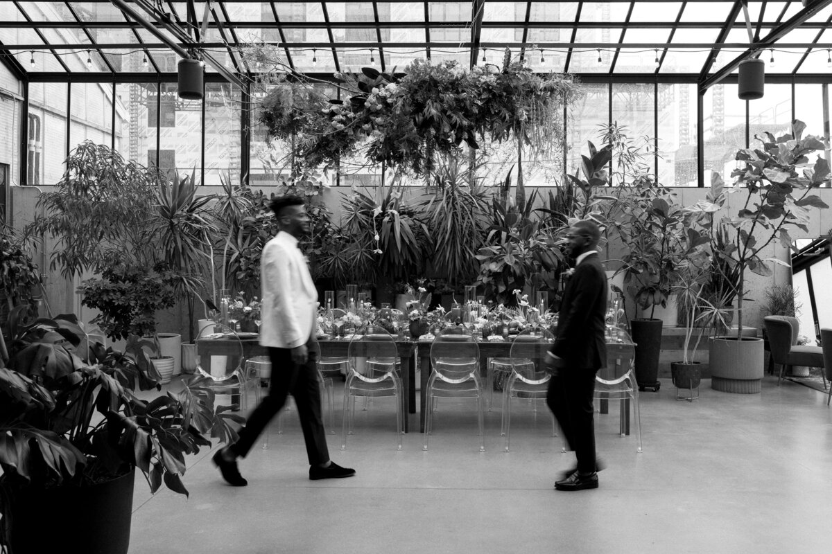 LGBT grooms walking toward each other in the Tinsmith solarium at their wedding in Madison