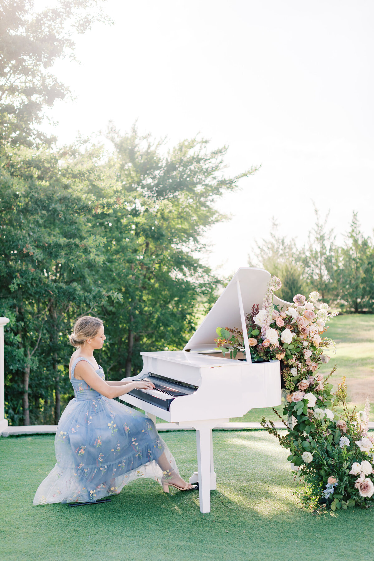 elegant-woman-playing-white-piano-outdoors-with-floral-decor