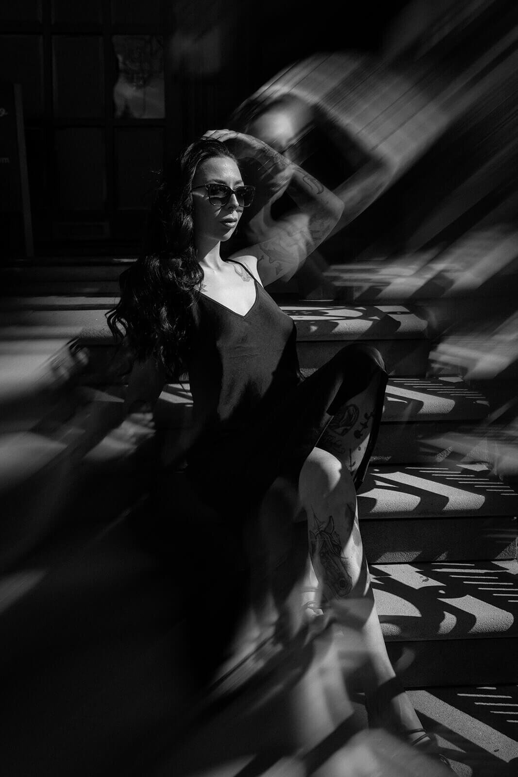 A lady in a black dress and sunglasses sat down with an lens effect making the photograph more dramatic