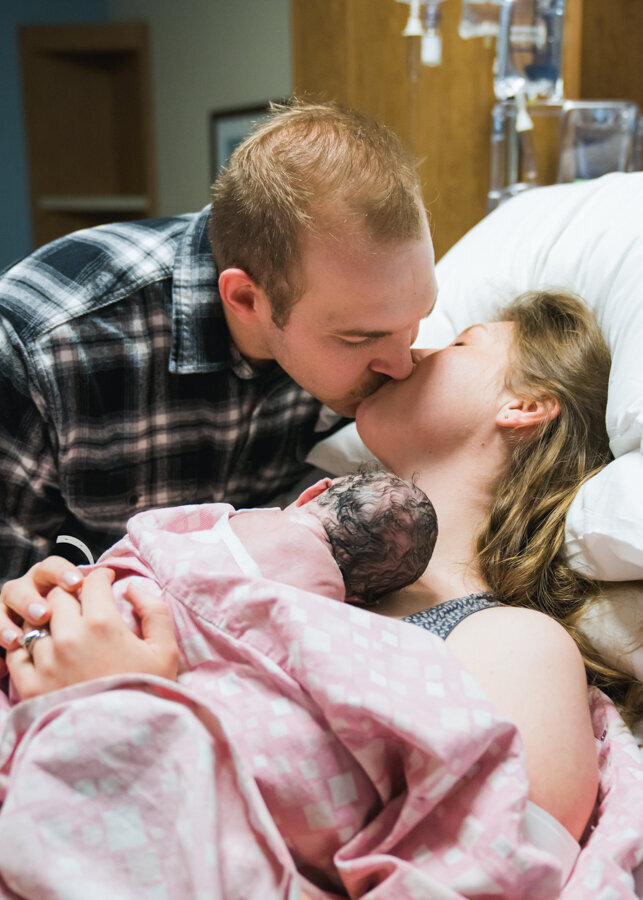 A couple kiss to celebrate their new baby girl. Birth story by Diane Owen Photography.