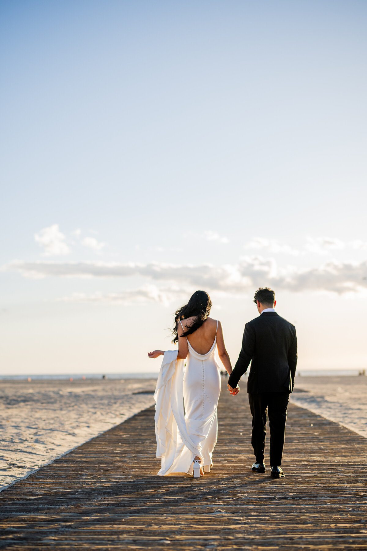 Professional Bay Area wedding photography featuring an artistic photograph of a couple walking from together towards the beach on a boardwalk