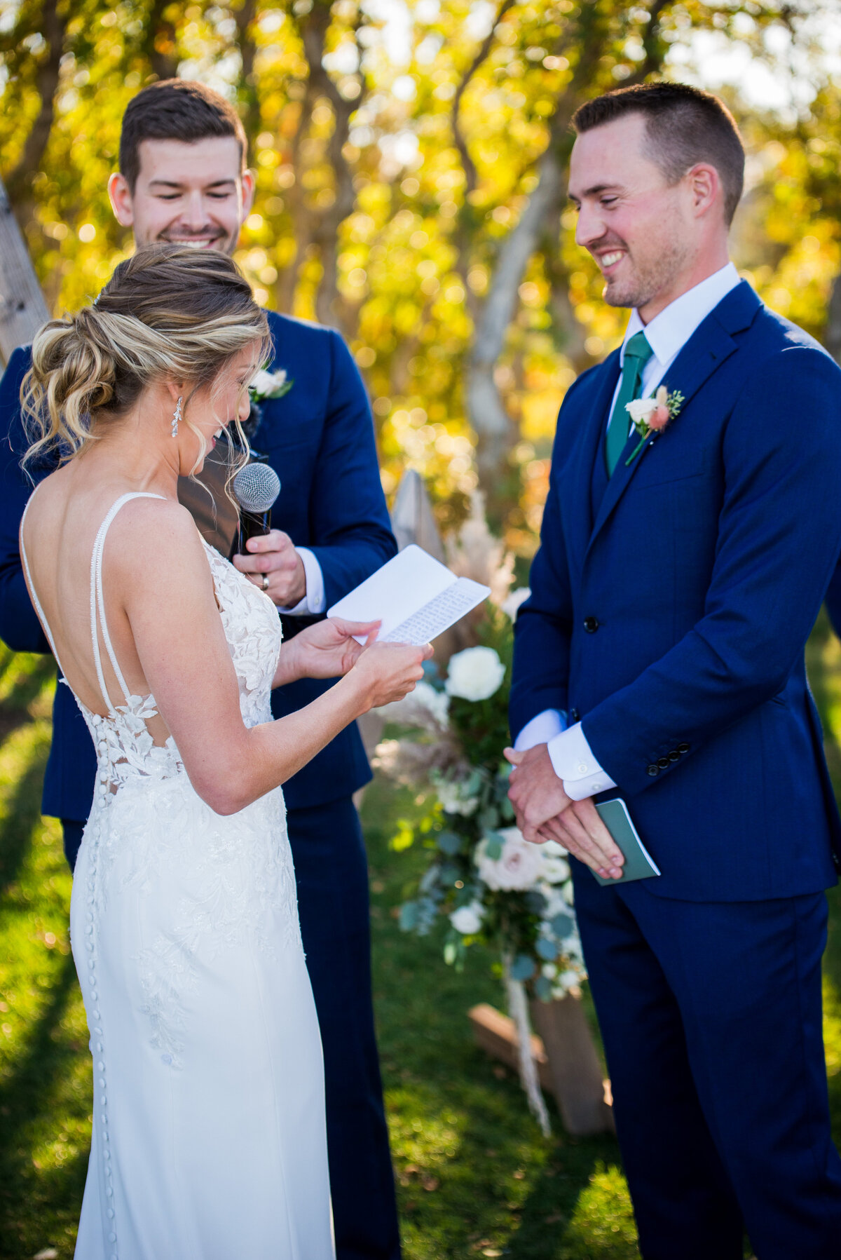 A bride reads her vows to her smiling groom during their ceremony at The Oaks at Plum Creek.