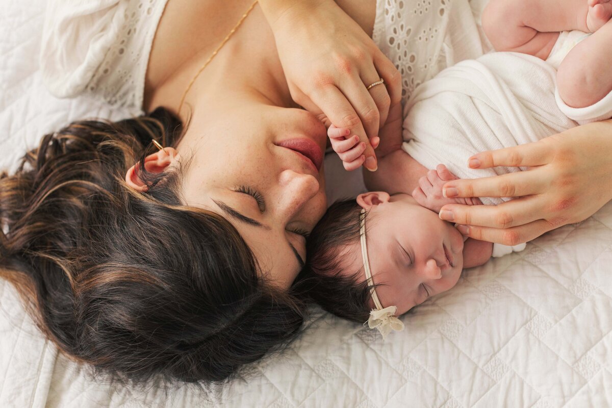 mother holding baby sweetly on bed in-home newborn session Cincinnati, OH