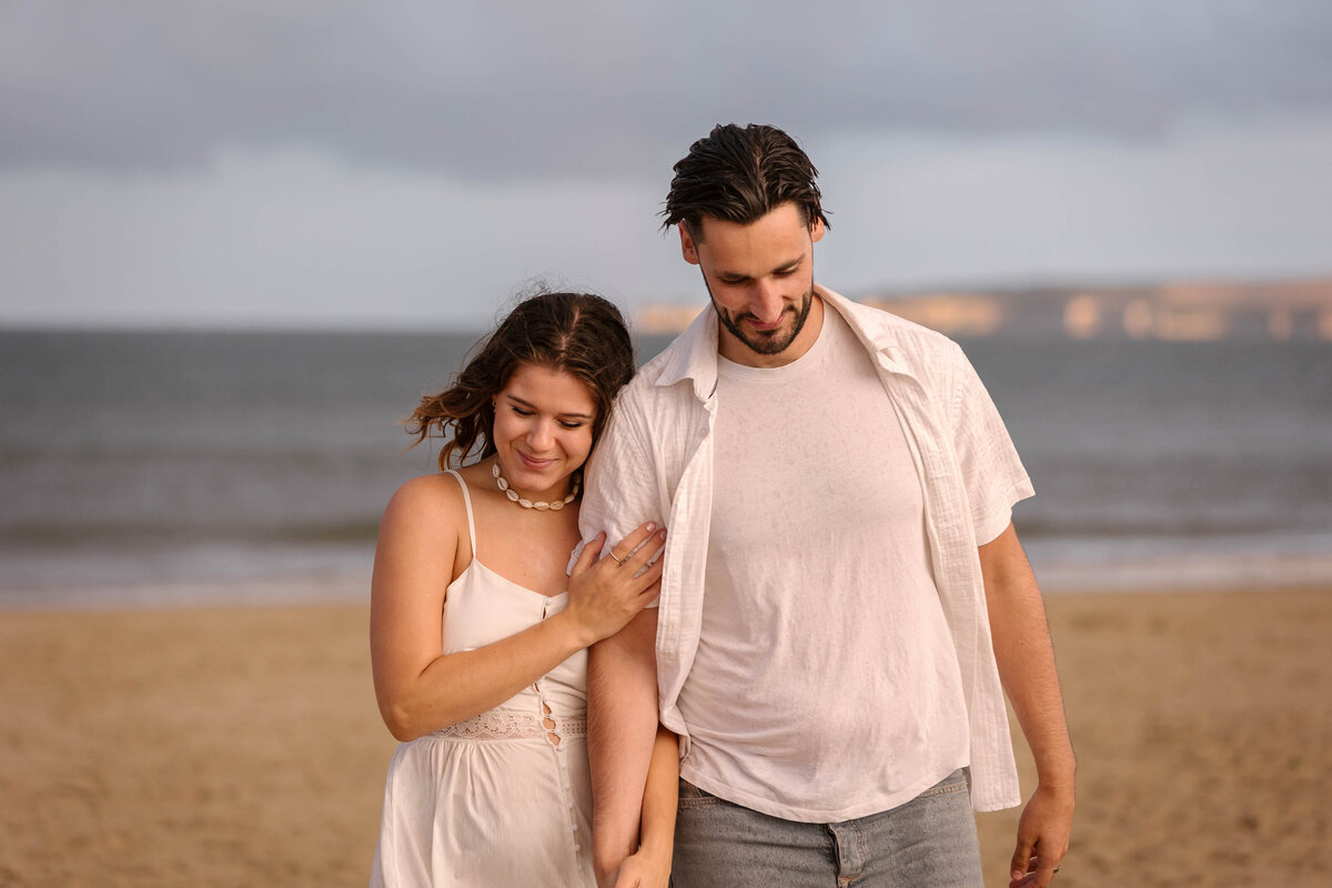 A couple on the beach walking arm in arm in Bournemouth