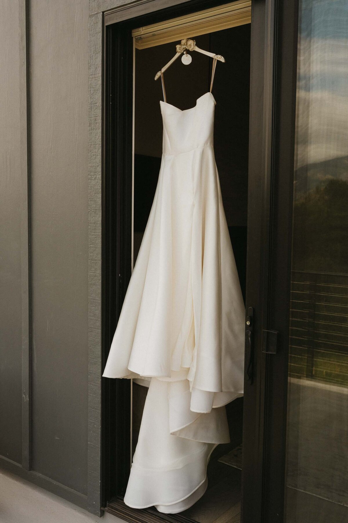 White wedding dress on a hangar outside of an AirBnB during a Destination Wedding - Bozeman, Montana