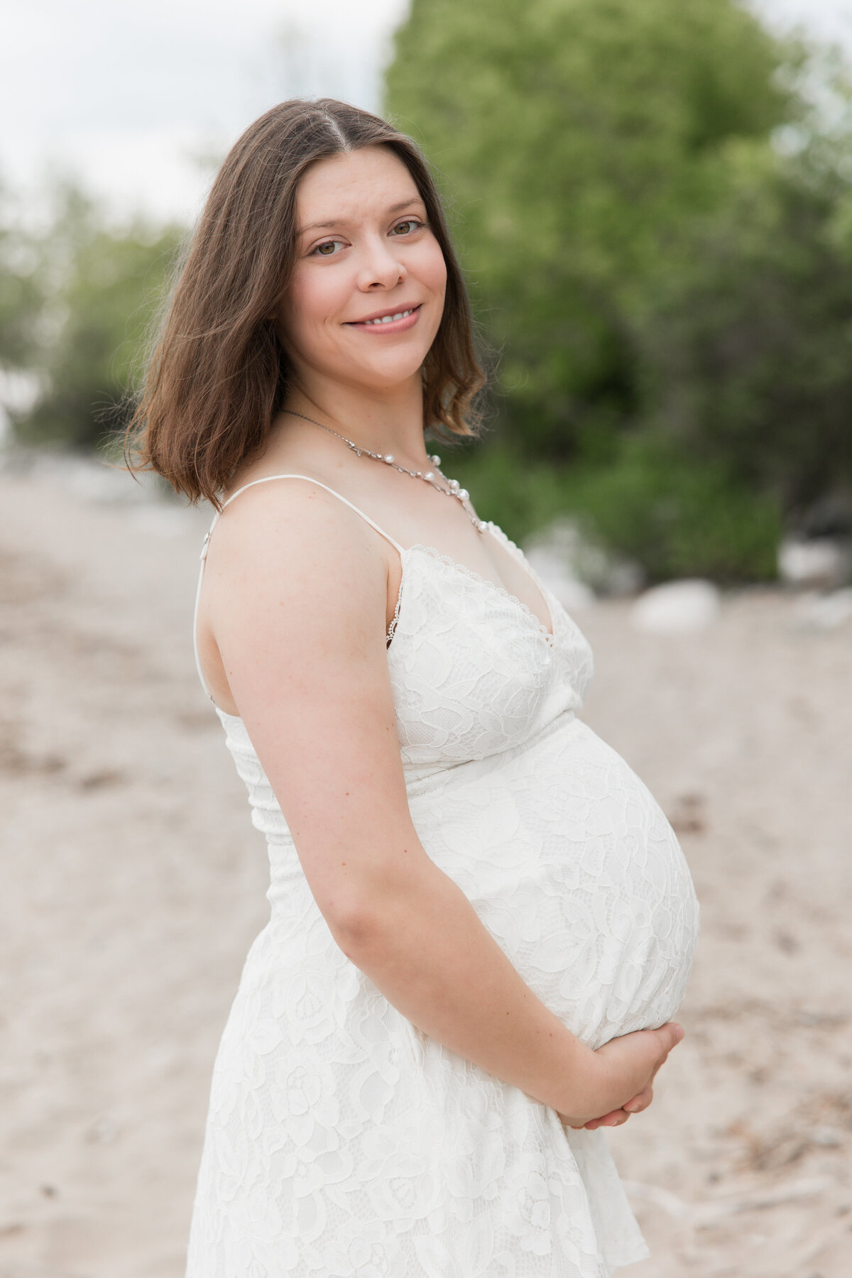 Expectant mother holding her baby bump and smiling at the camera