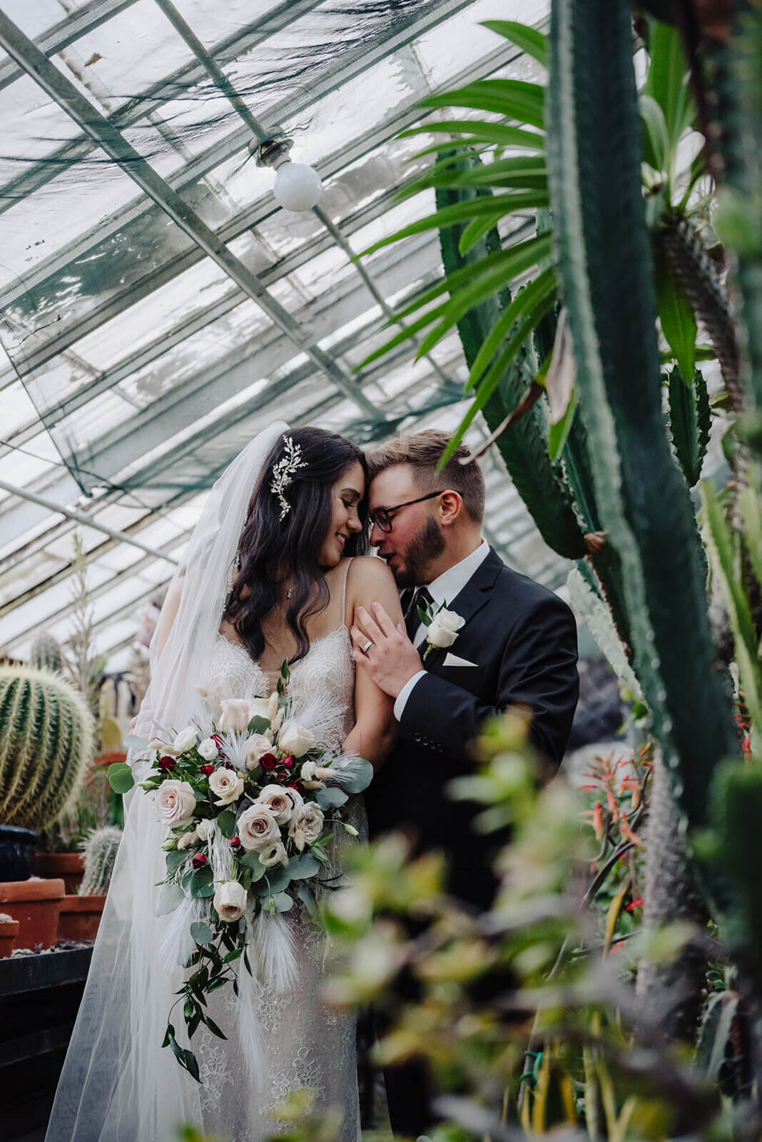 Bride and groom in a large greenhouse with cactus around them