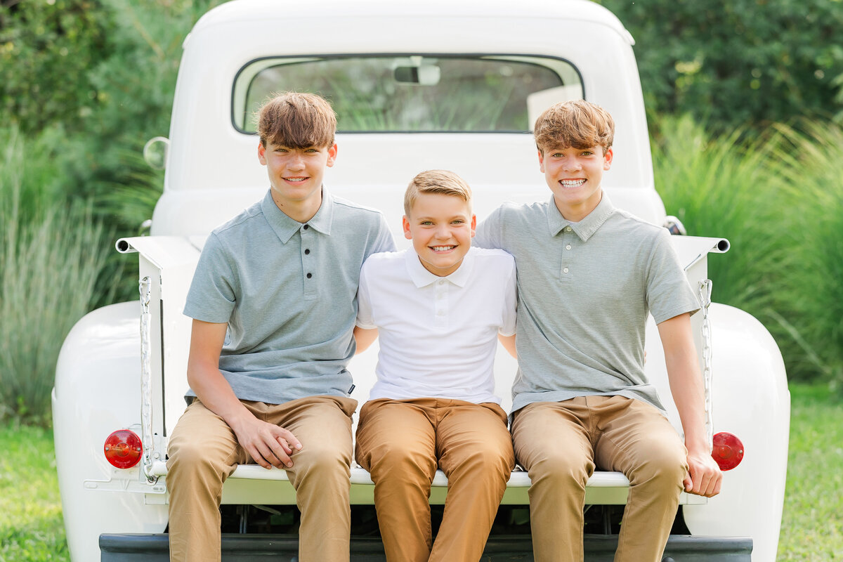 Brothers sitting with their arms around each other’s shoulders for North East, PA, family pictures outdoors.