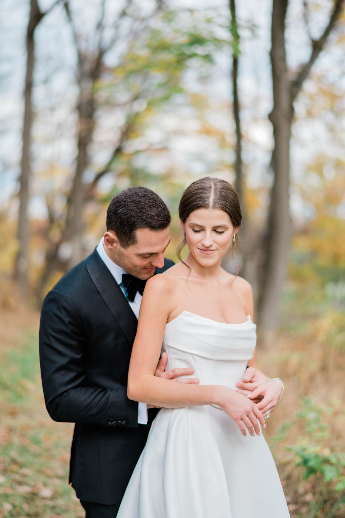 The groom wraps his arms around the bride’s waist as she smiles