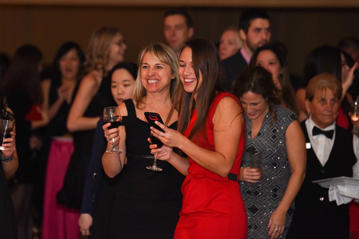 Guests laughing and enjoying a gala evening with wine, captured by a corporate event photographer in Toronto
