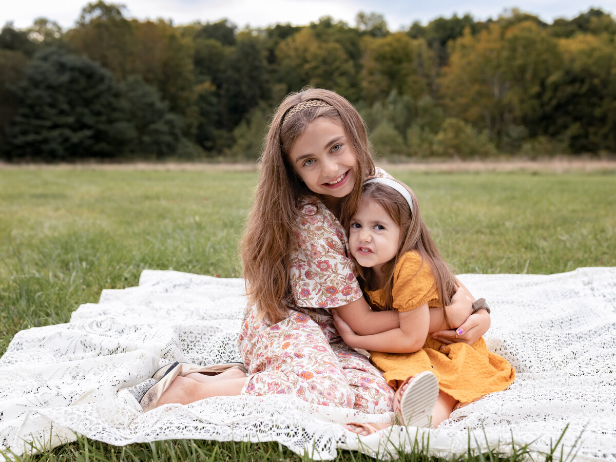 sisters sitting on lace blanket for family photos