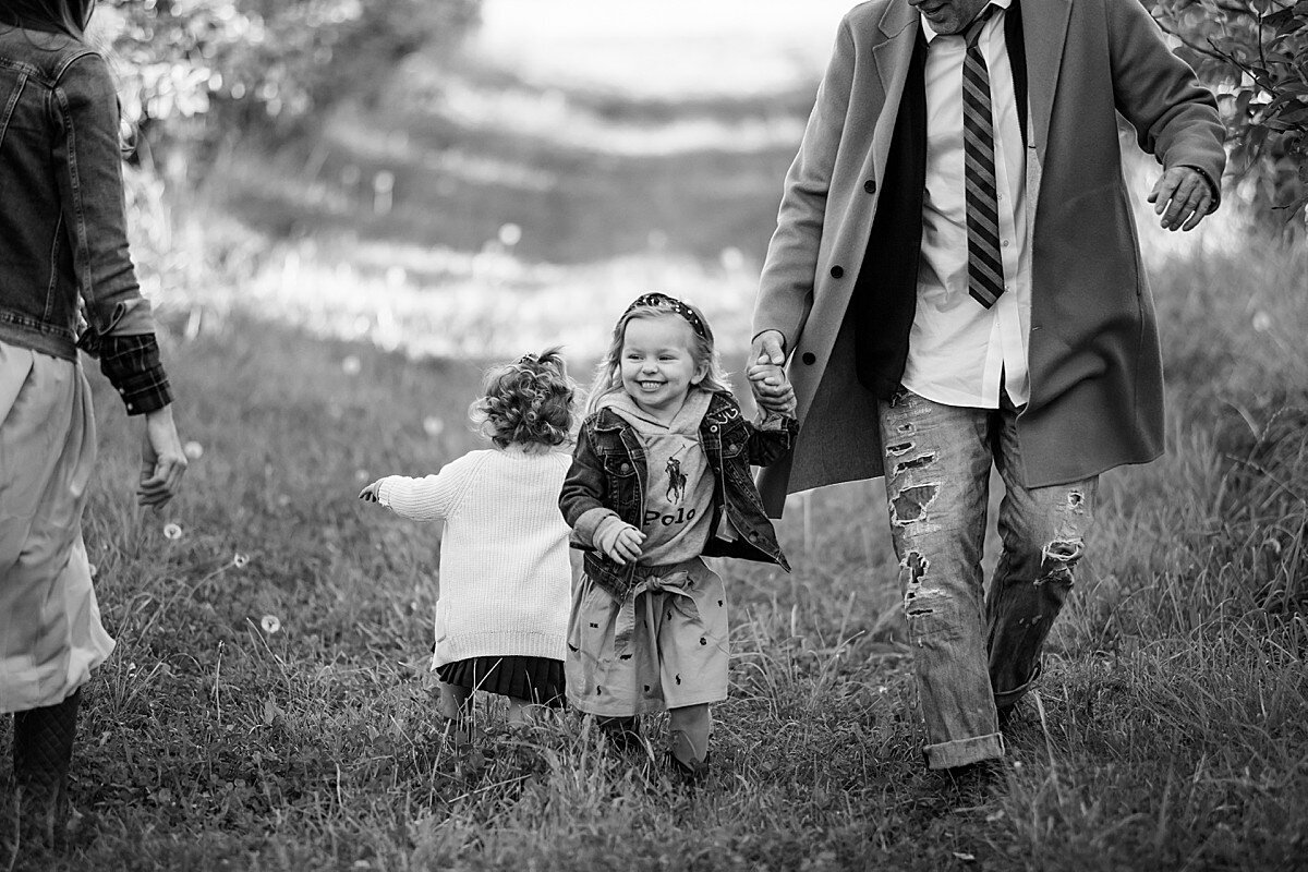 Well-dressed family walking in orchard with little girl