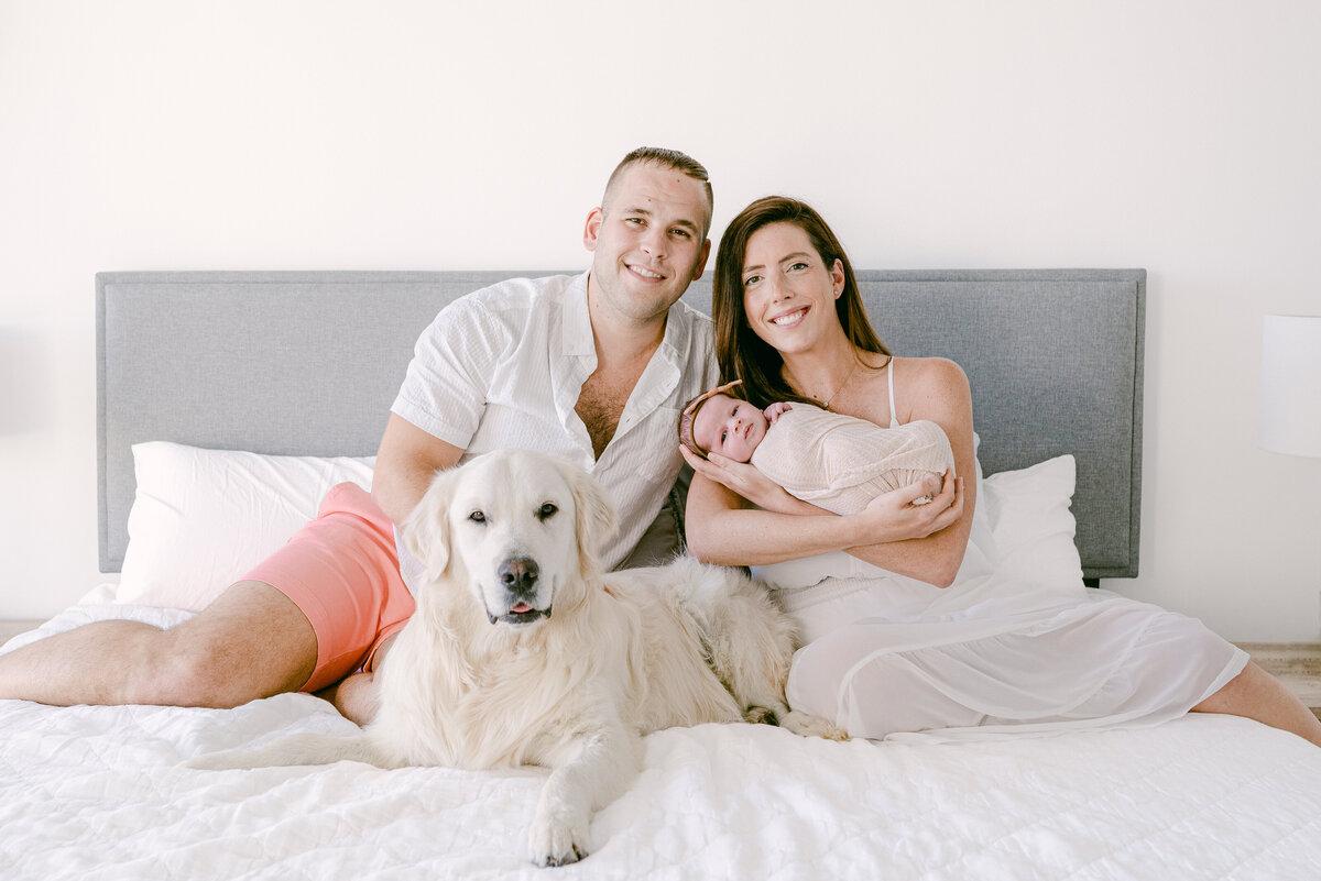 Family with dog and newborn smiling looking at camera