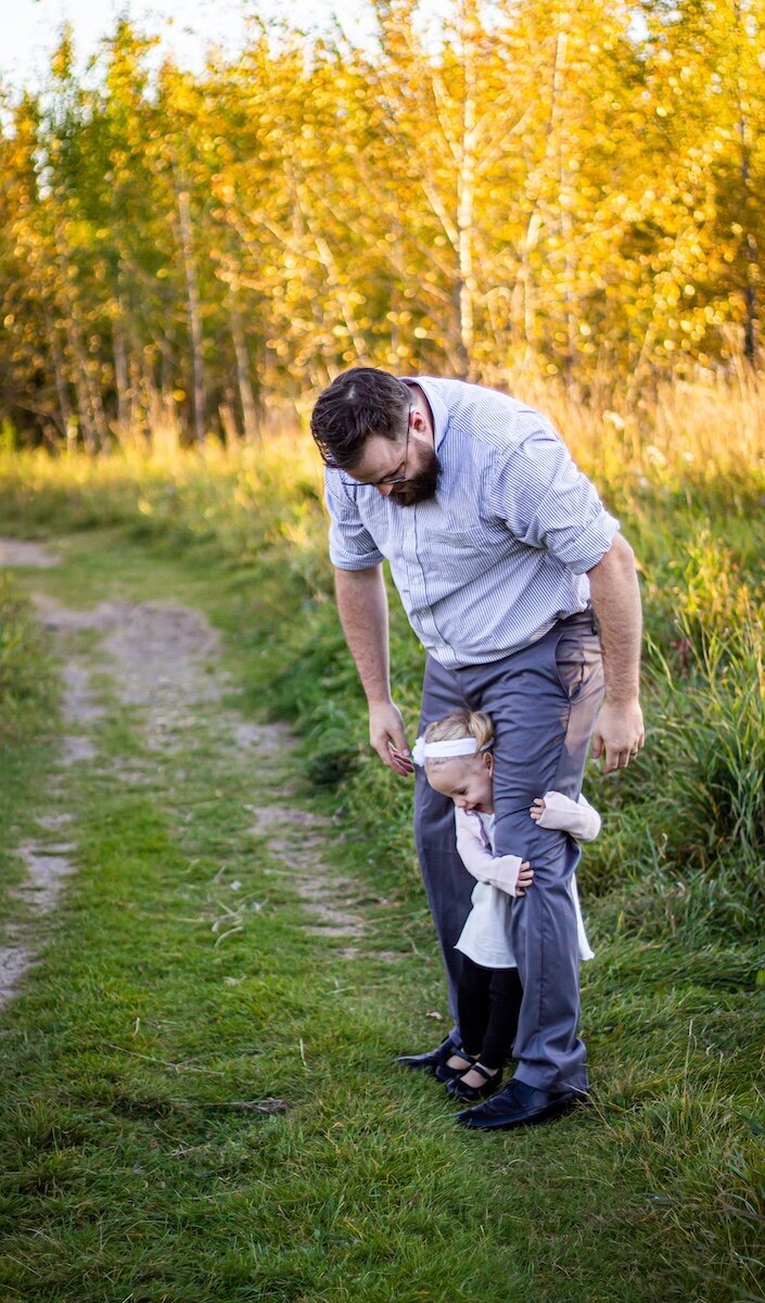 a dad plays with his toddler daughter between his legs