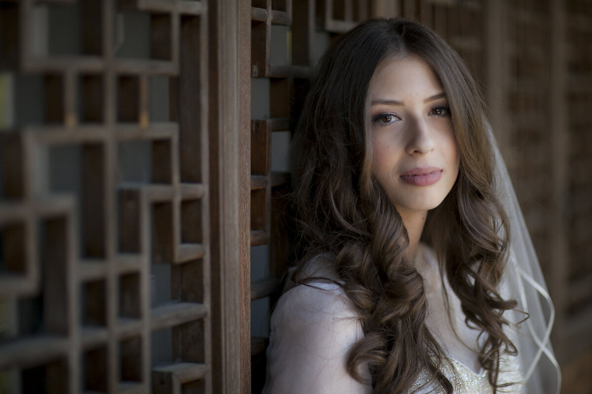 A person in a wedding dress leaning against a wooden barrier 