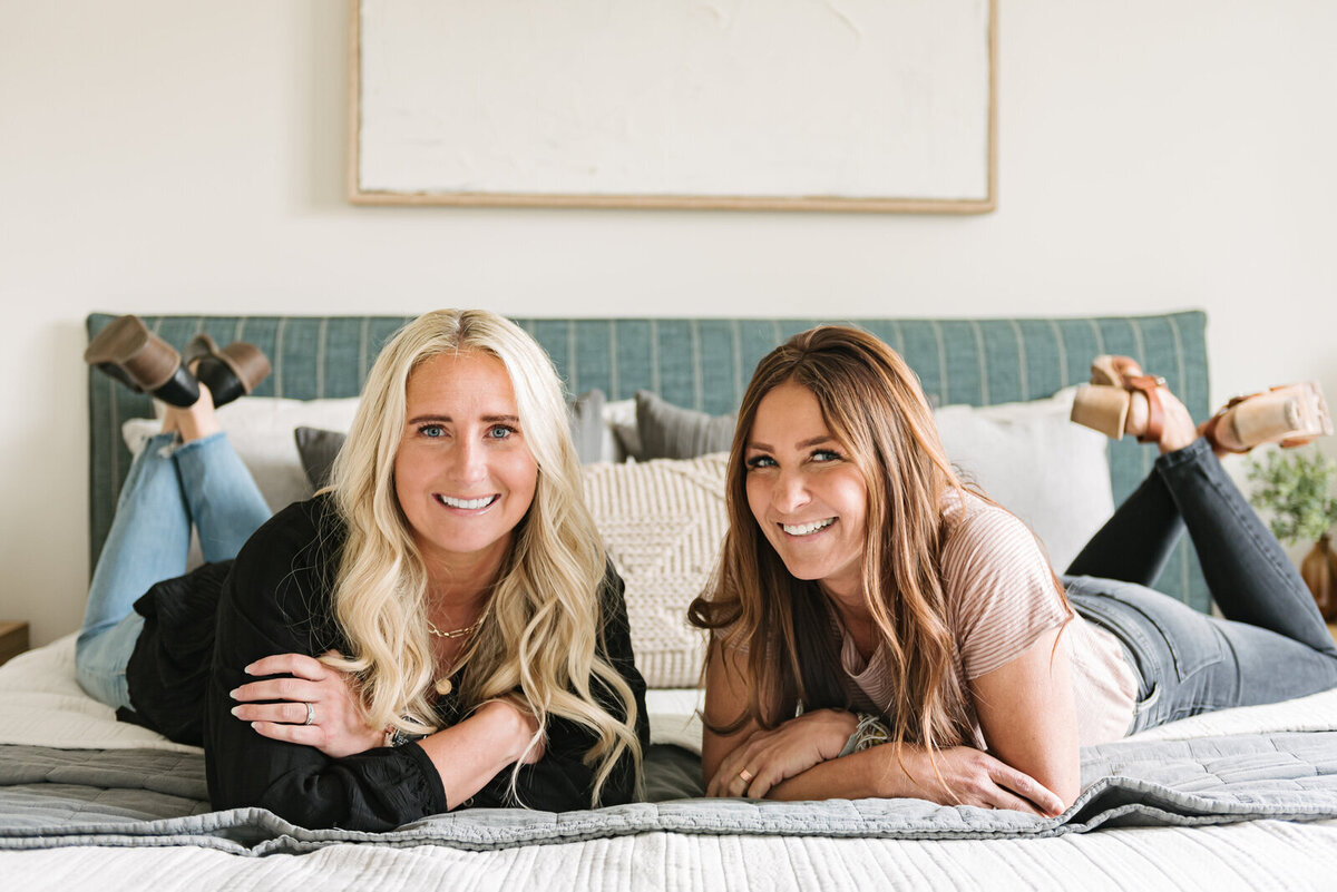Shop 1425 founders Muriel and Kendra from Utah, lying on a bed from the shop furniture collection.