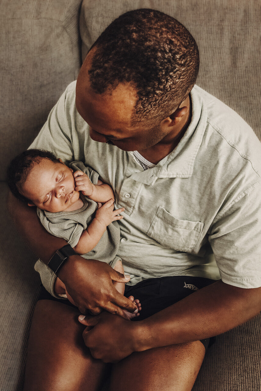 Newborn baby sleeping in father's arms, both wearing green: Statesboro Georgia lifestyle newborn photography