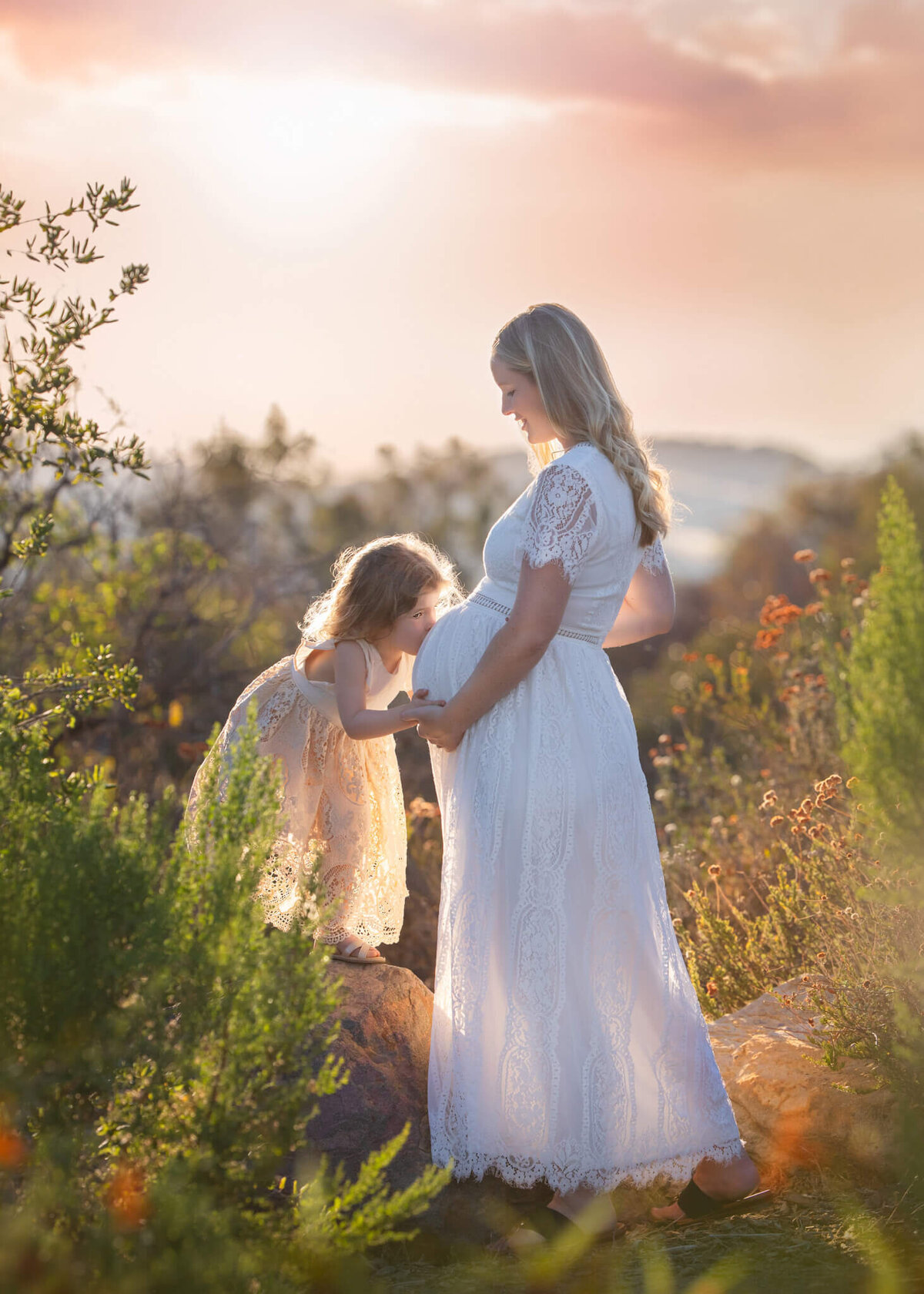 Daughter kissing moms baby bump at sunset photographed by Los Angeles Maternity Photographer Elsie Rose Photography