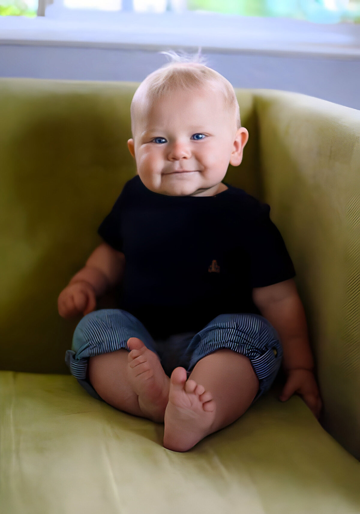 9-month-old baby smiling while sitting on a couch — natural, candid photography by San Francisco Bay Area baby and family photographer.