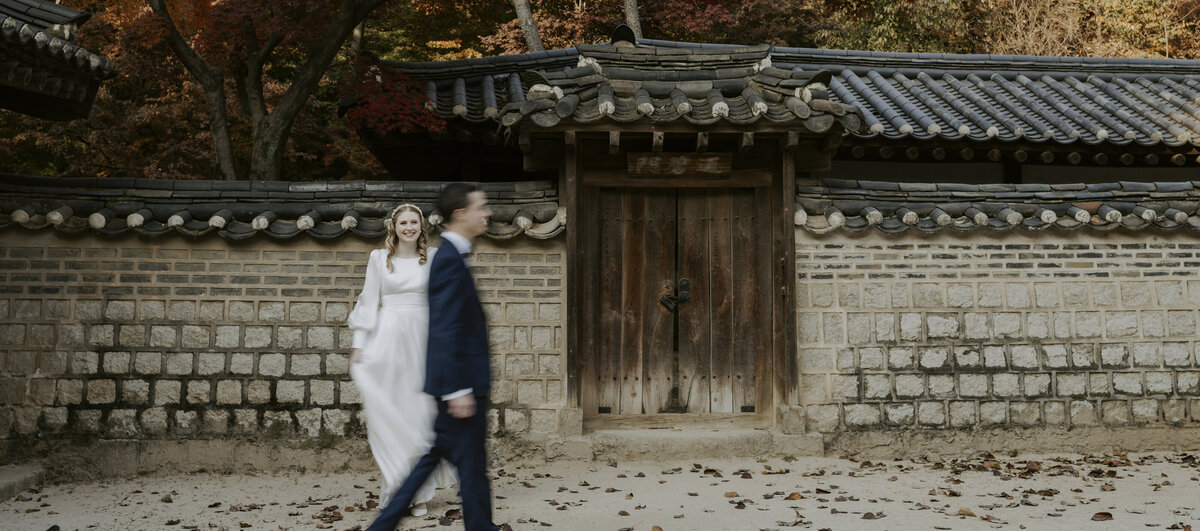 the bride is standing while the groom passed by her outside a korean traditional house