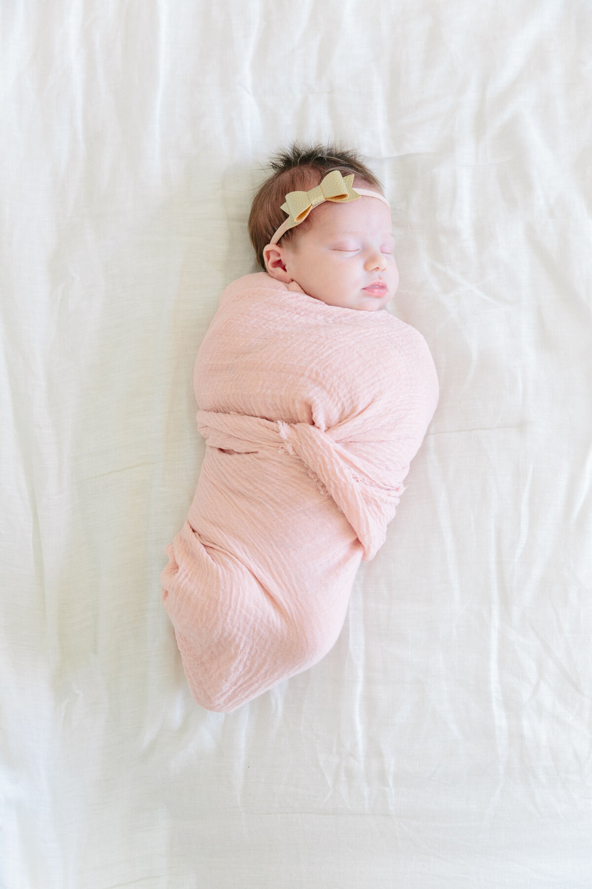A newborn swaddled in a pink blanket