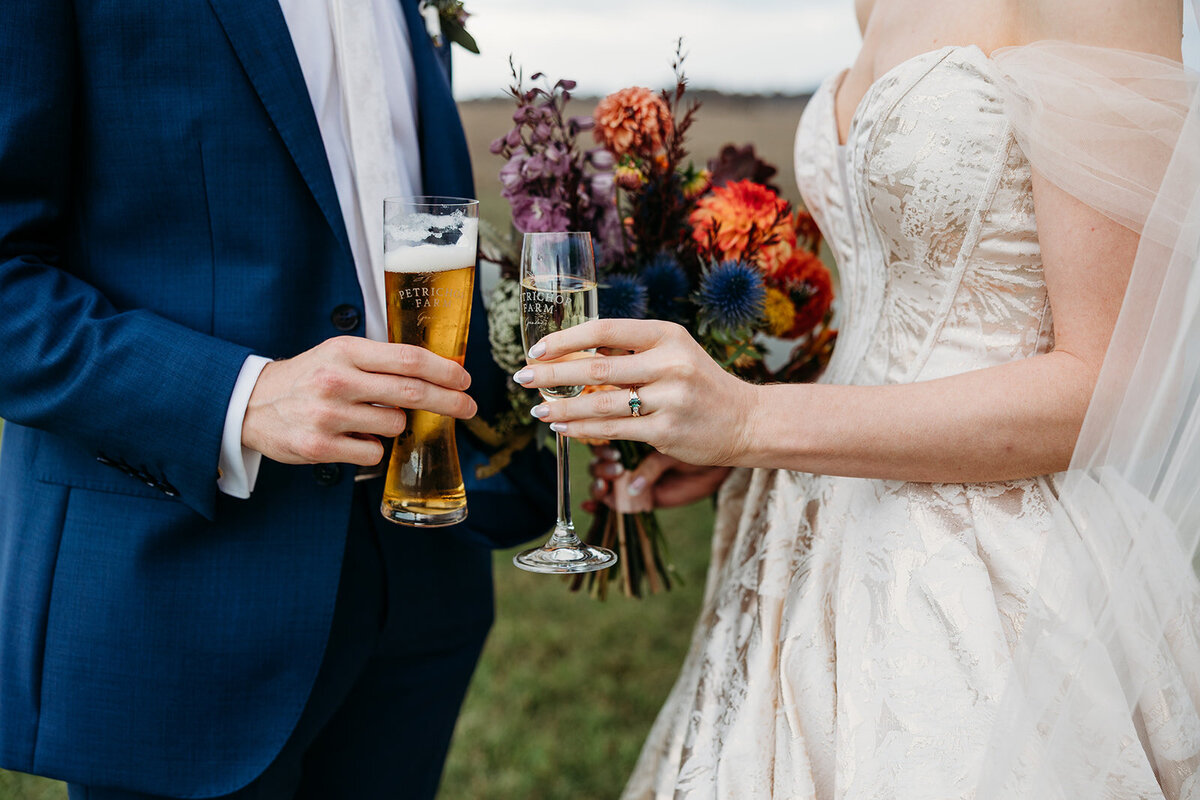 Bride and groom with champagne and beer. Close up photograph of hands, bridal bouquet and wedding rings.