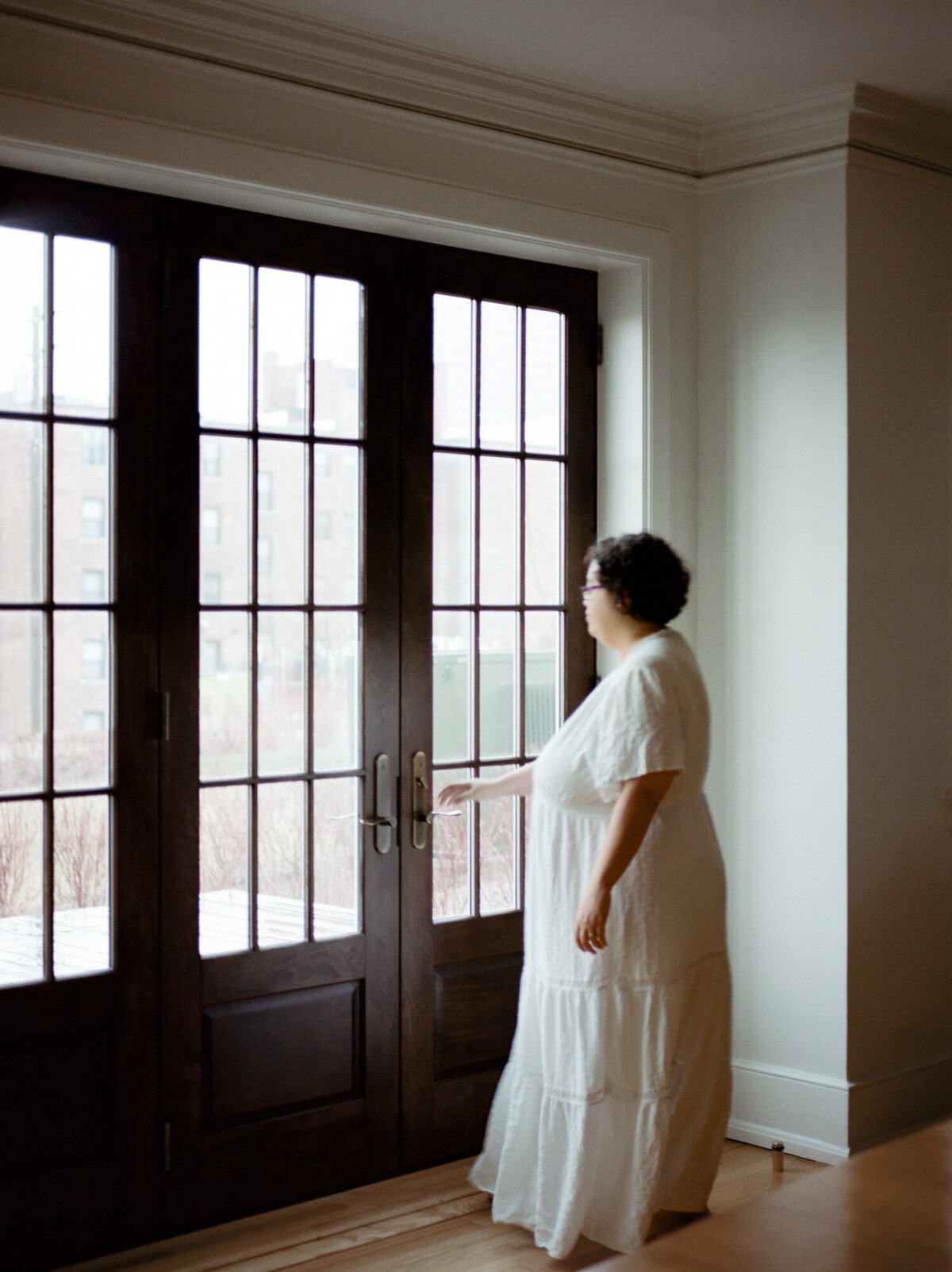 woman in white cotton long dress moves toward historic windows, ALEO Detroit