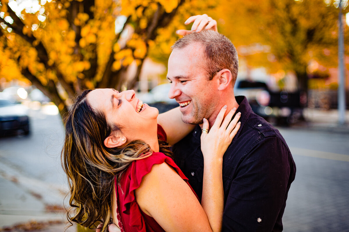 A couple laughs out loud during their fall engagement photos in downtown Toledo Ohio. Photo By Adore Wedding Photography. Toledo Wedding Photographers