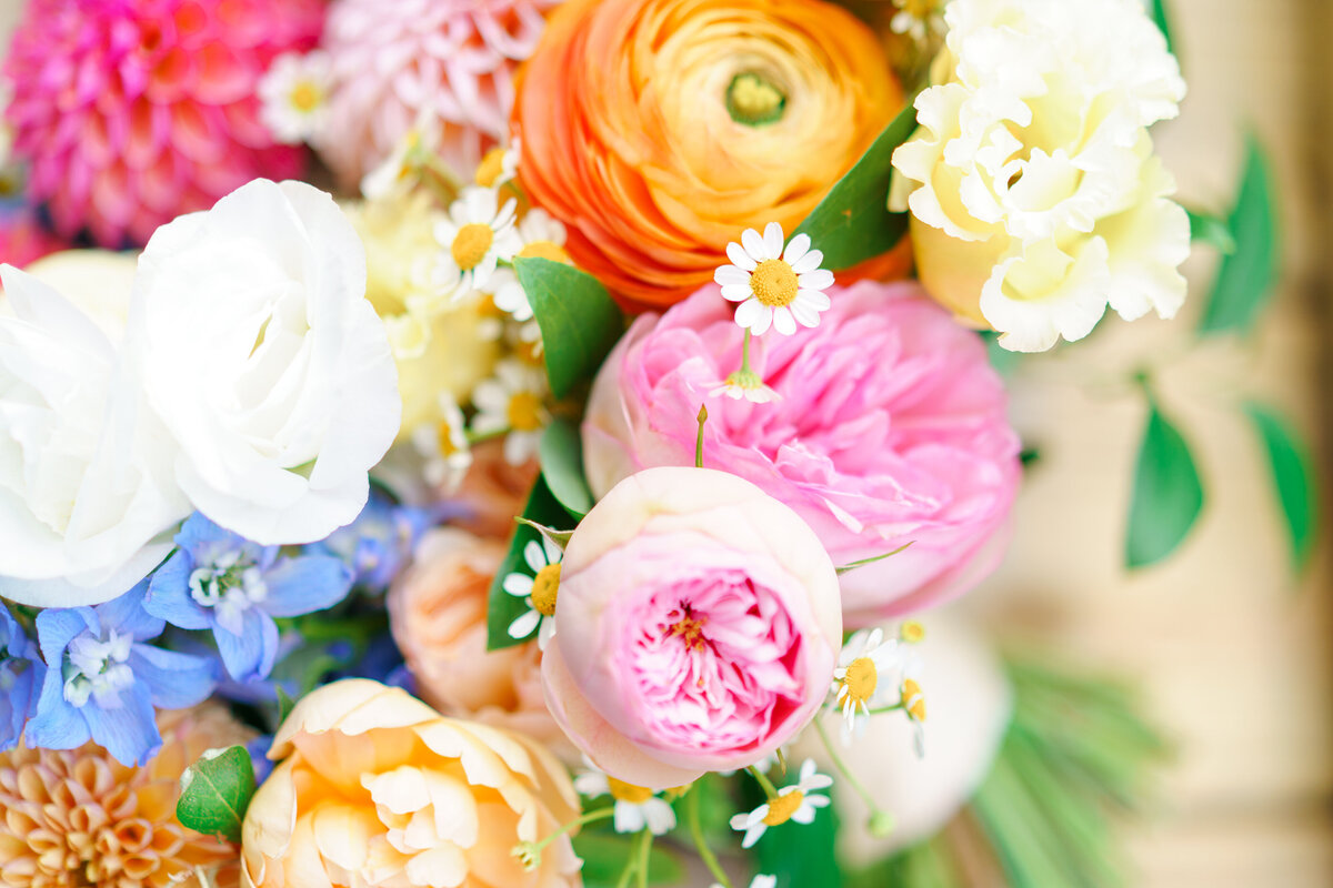 Colorful wedding bouquet with pink, blue, orange, white, and peach hues.