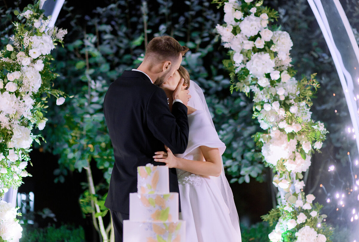 side-view-newlyweds-kissing-during-wedding-celebration-background-decor-with-flowers