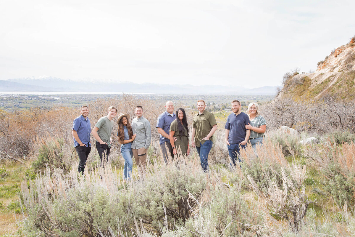 family of adults wearing blue and green posing on mountain with view of Utah Lake, captured by Las Vegas family photographer, Jessica Bowles