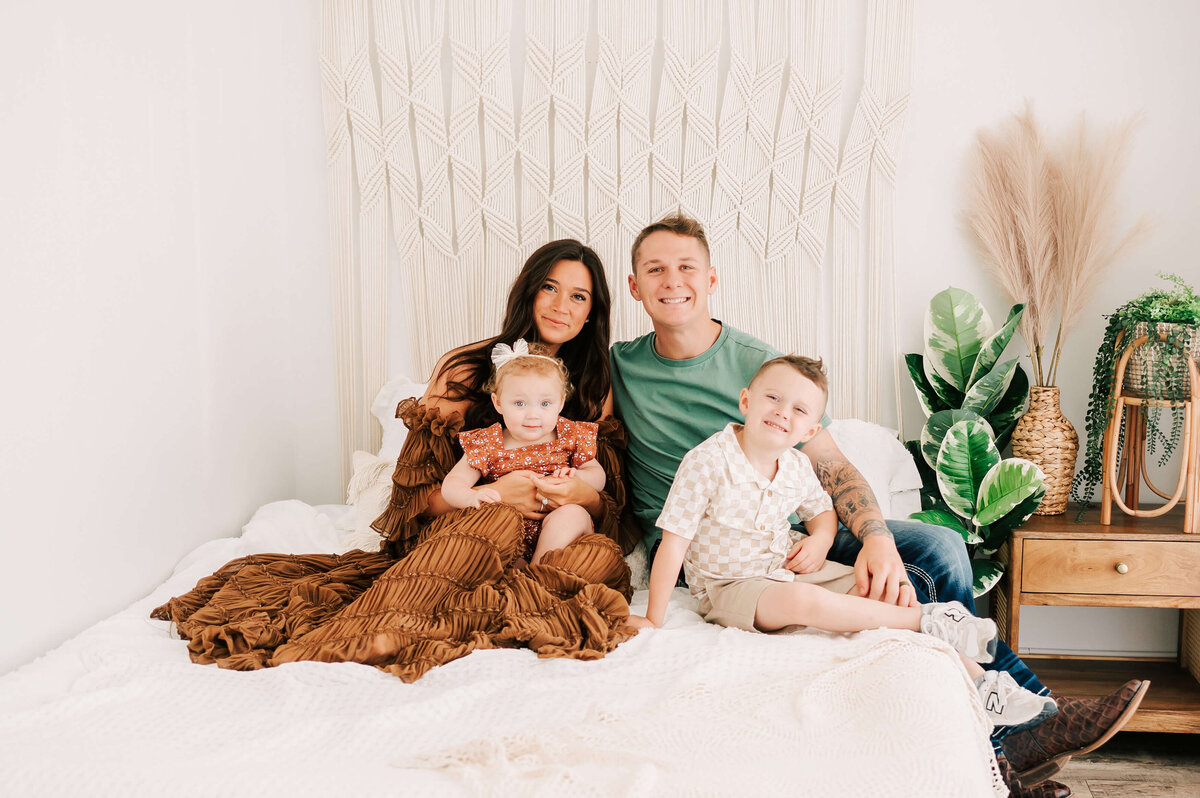 Springfield MO family photographer Jessica Kennedy of The XO Photography captures family cuddling on bed in photography studio