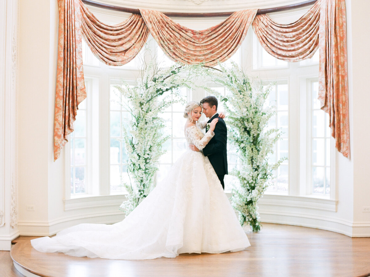 couple embrace in front of bay windows