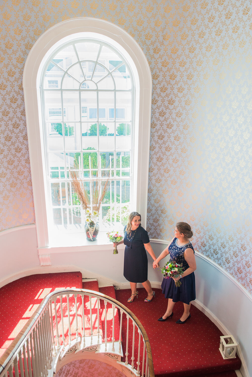 Gay couple on grand stairway with red carpet looking at each other