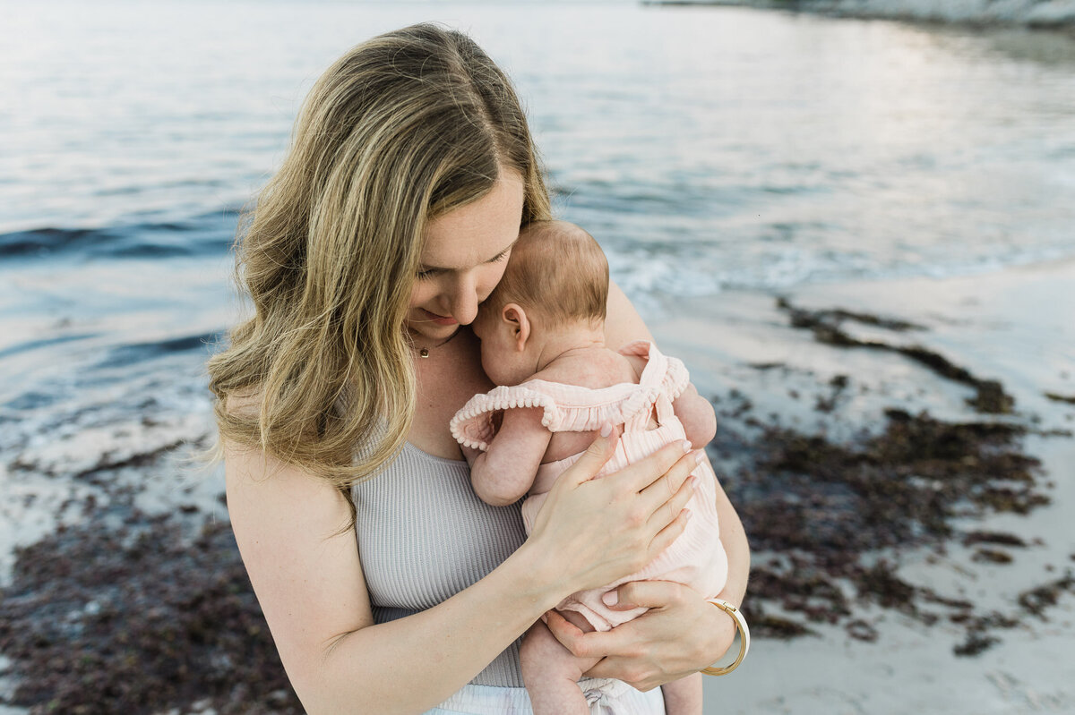 Woman holding new baby on beach.