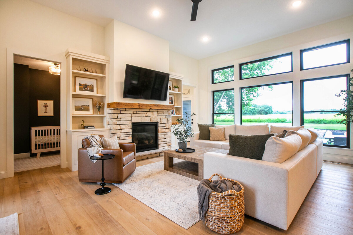 Cozy living room in Otsego custom home with fireplace, built-ins, and large windows