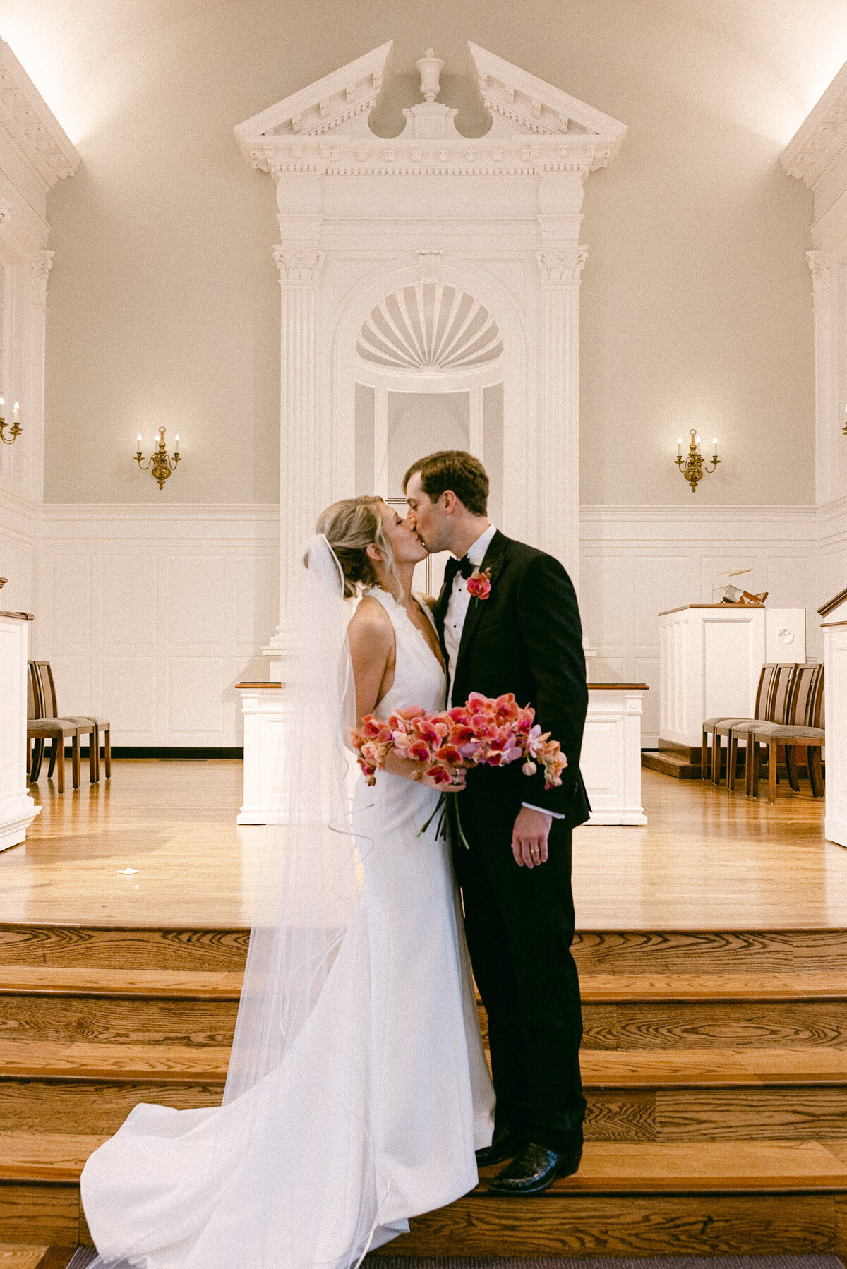 A wedding day photo of the bride and groom kissing after their ceremony