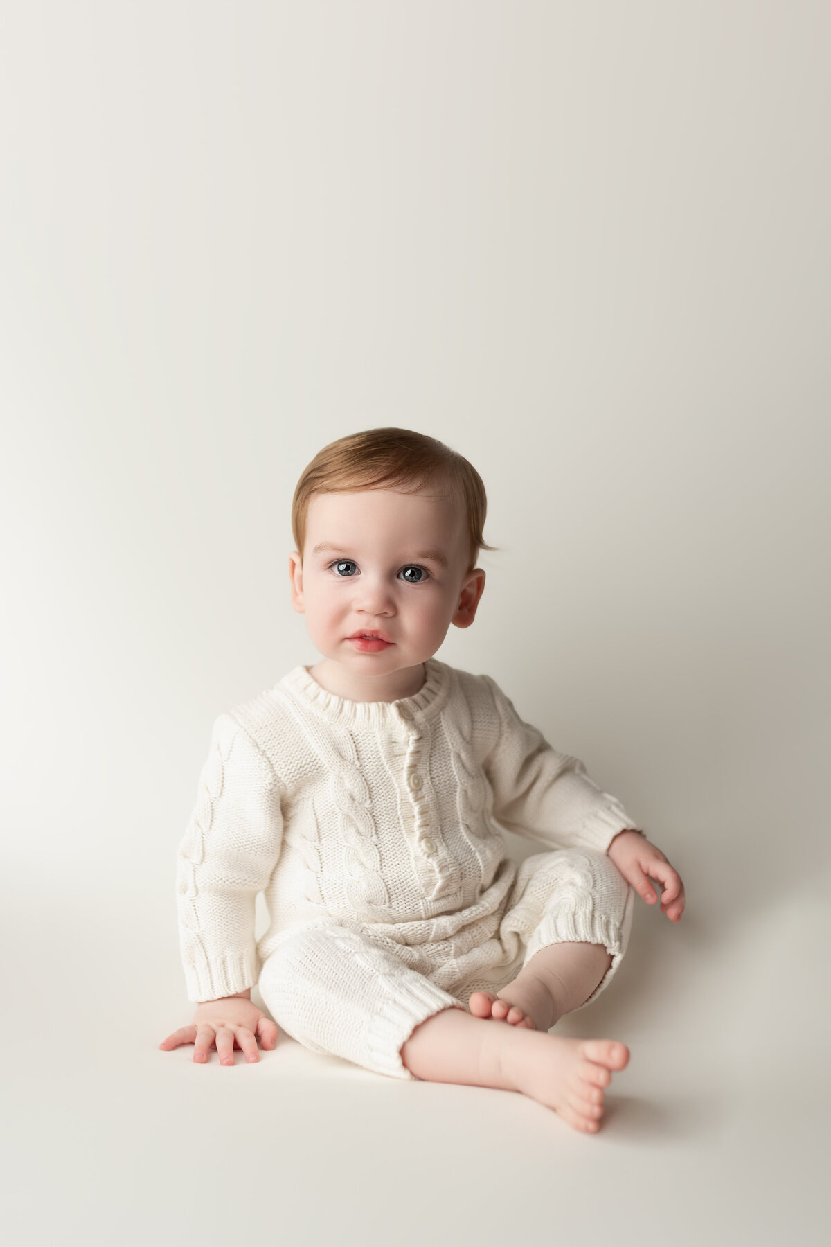 Timeless milestone portrait of a baby boy in a minimalist cream setting—capturing classic elegance in Paris, Ontario.