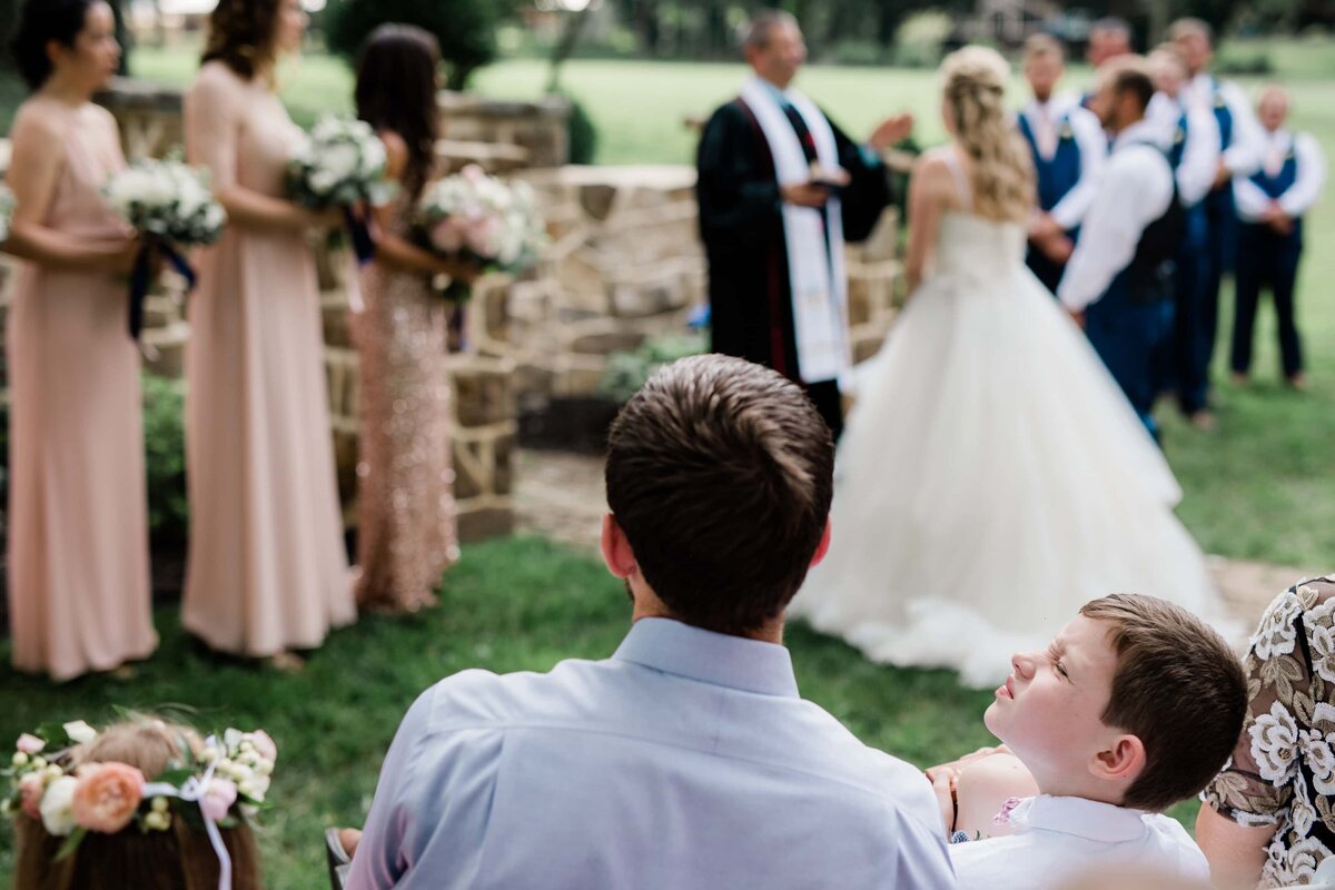 Candid moment of ring bearer bored during ceremony at Historic Shady Lane