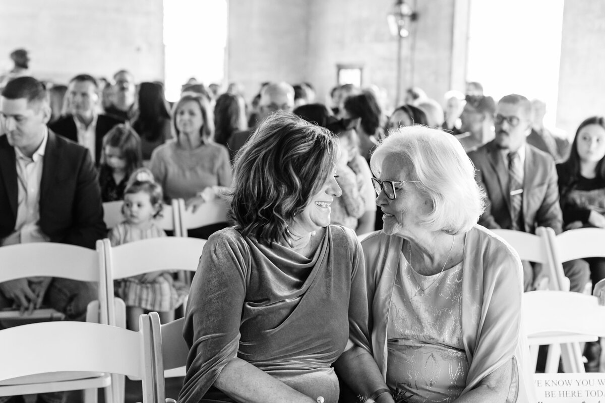Candid portrait of brides mother and grandmother sharing a smile waiting for the bride to walk down the aisle at Olde Dobbin Station.