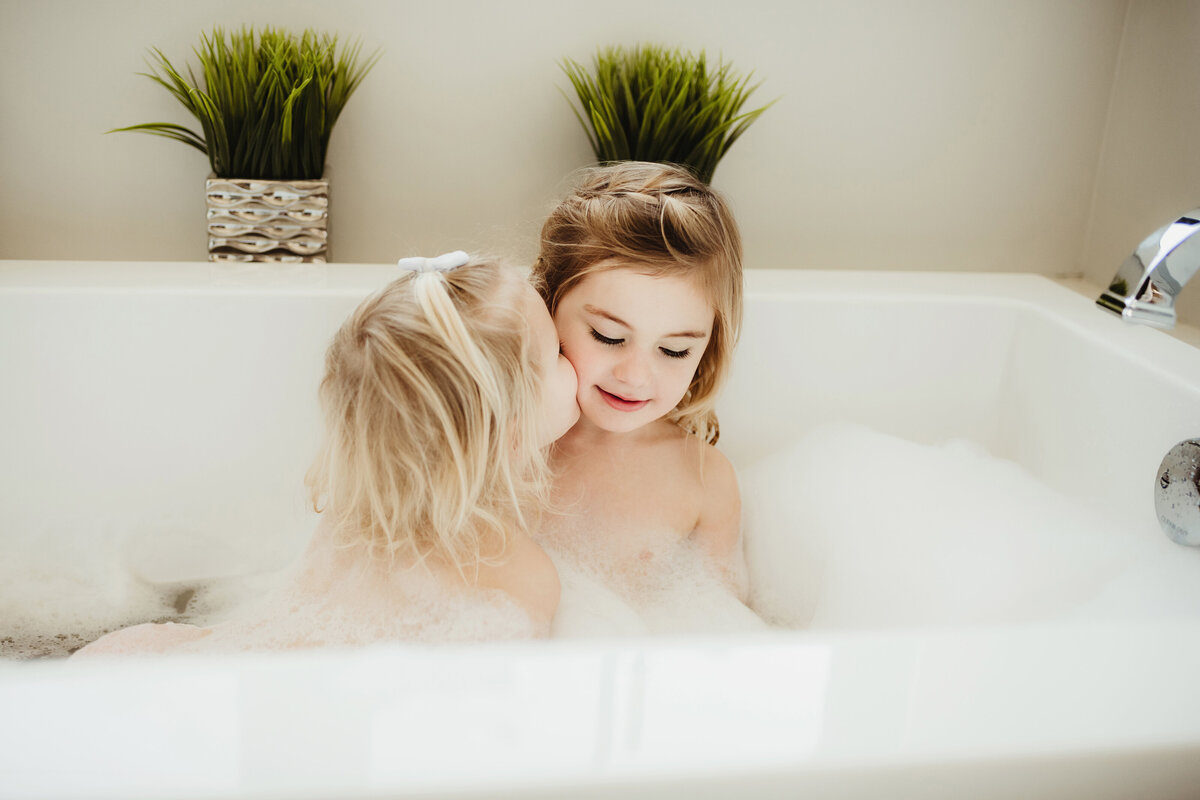 little sister kissing big sister in tub