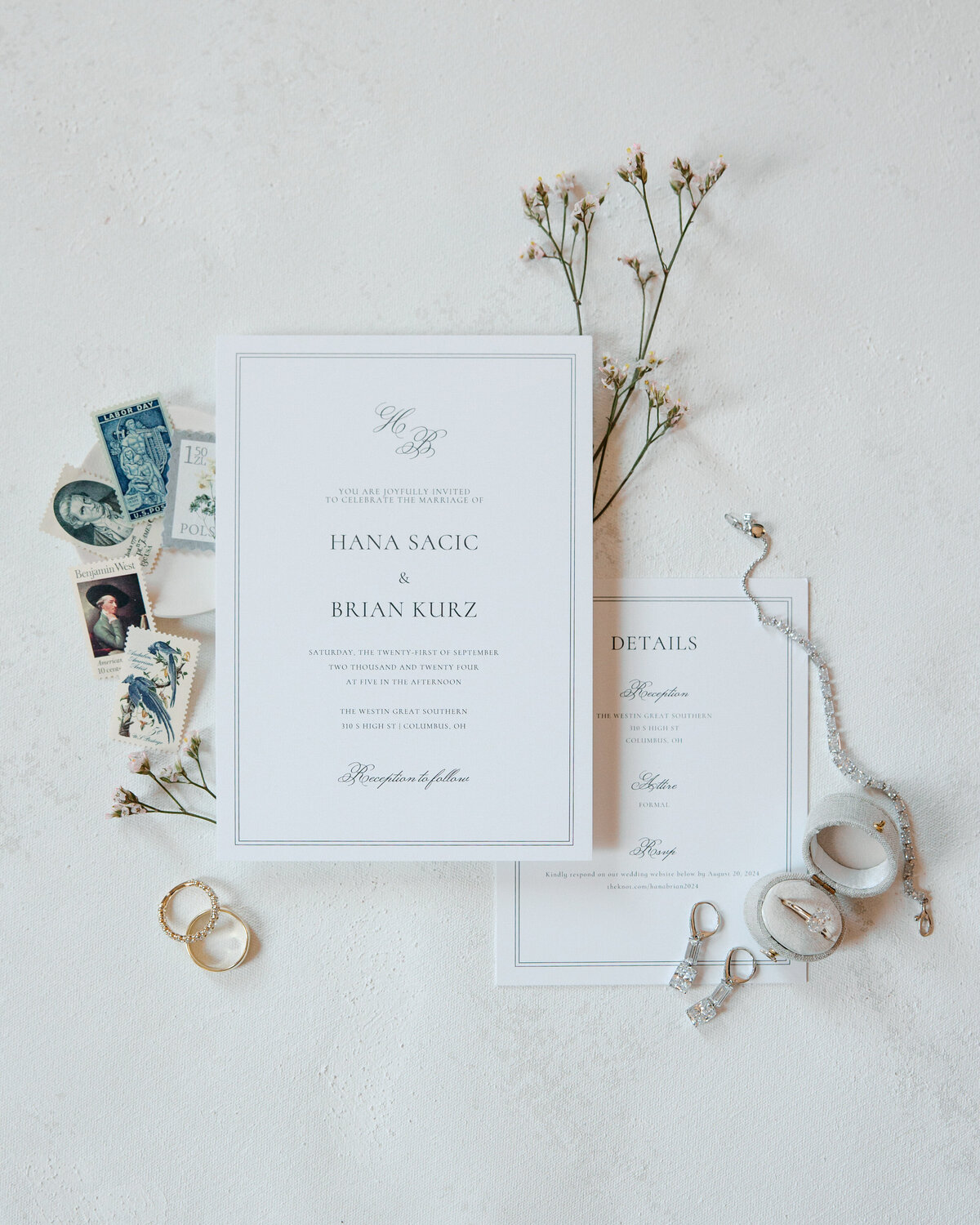Flat lay of elegant wedding invitation suite, rings, stamps, and flowers styled by a Philadelphia wedding photographer.